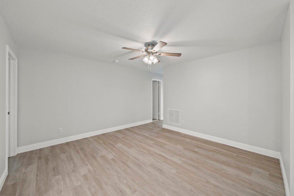 Empty bedroom with ceiling fan and hardwood flooring